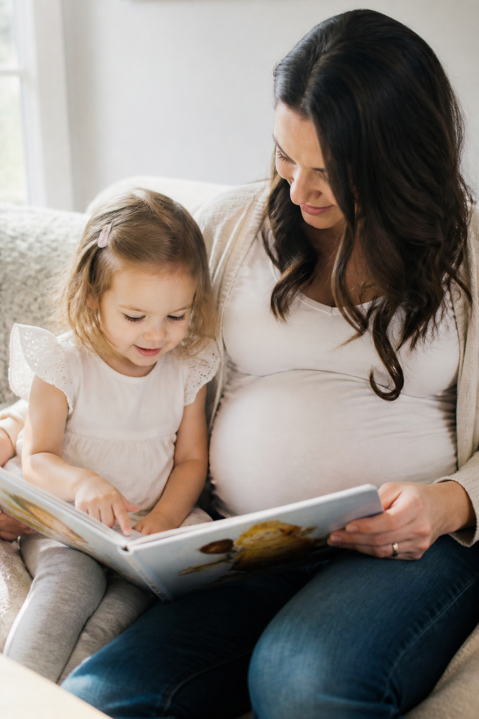 Sibling Reading a Book to the Bump Announcement